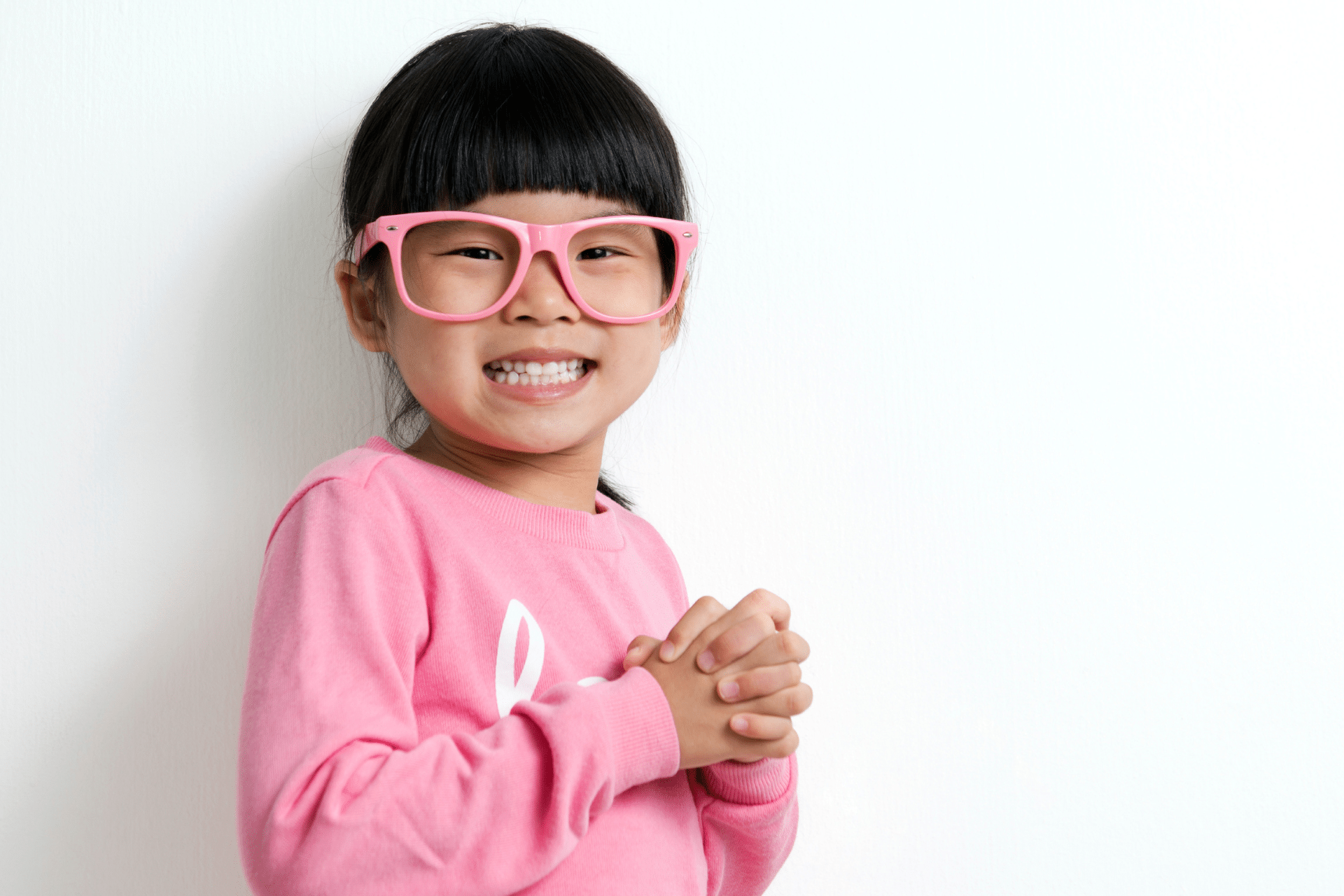 Smiling young girl wearing pink glasses showing off her healthy teeth